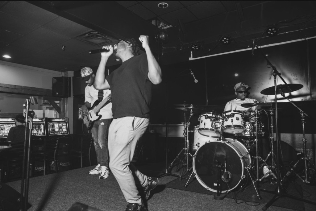 First Sunday performing live - vocalist, bassist, and drummer on stage
